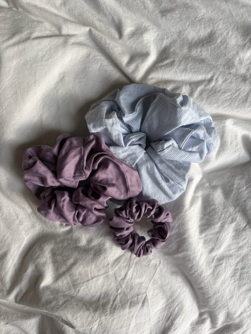 Collection of handmade fabric scrunchies in various materials laid out flat