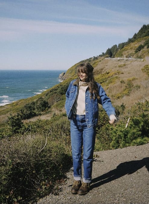 Woman in denim jacket, jeans, sweater and hiking boots