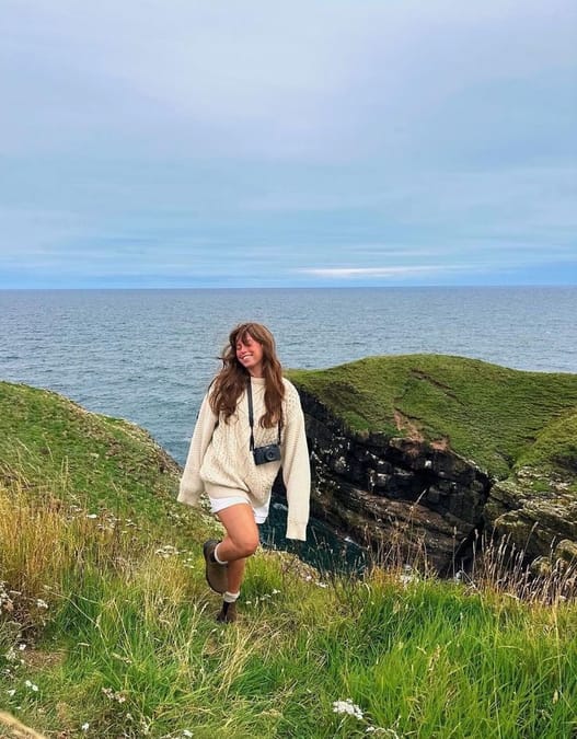 Woman in chunky cable knit sweater walking up a hill