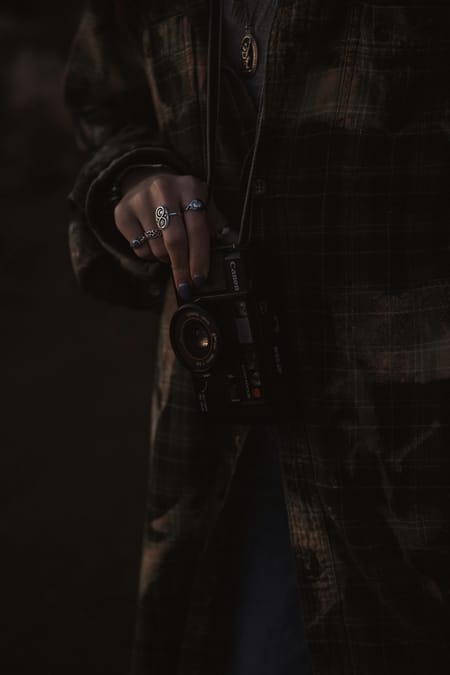 Moody image of rings on a hand holding a camera